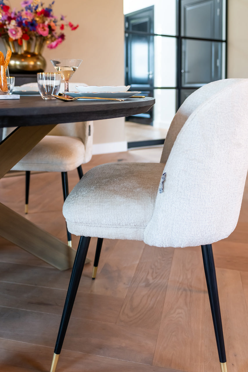 Contemporary dining chair in cream upholstery with black and gold legs