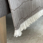 Andrew Martin tan Merino wool throw with geometric pattern and fringe