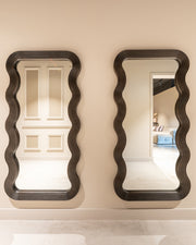 Modern wavy full length mirror with dark wood frame and sculptural curved design