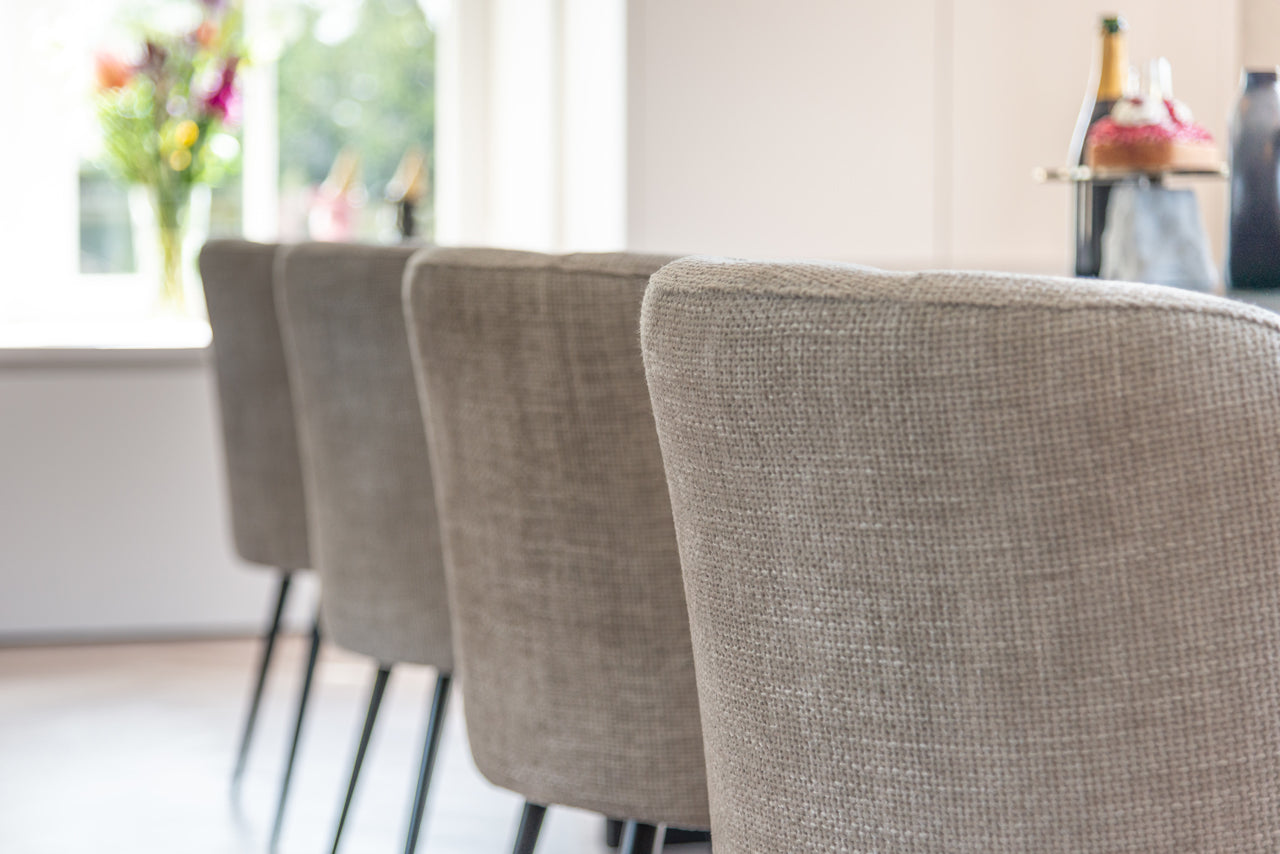 Contemporary upholstered dining chair in neutral fabric with black legs